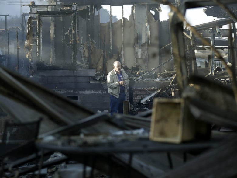 Dick Marsala looks through debris from his destroyed home after a wildfire roared through the Rancho Monserate Country Club Friday, Dec. 8, 2017, in Bonsall, Calif. 